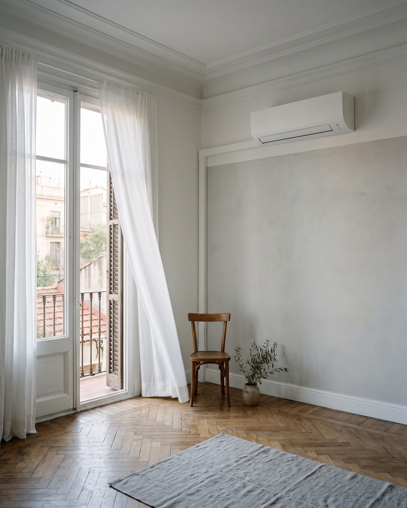 Salón de un piso del Ensanche con el aire acondicionado instalado en la pared y la puerta del balcón abierta